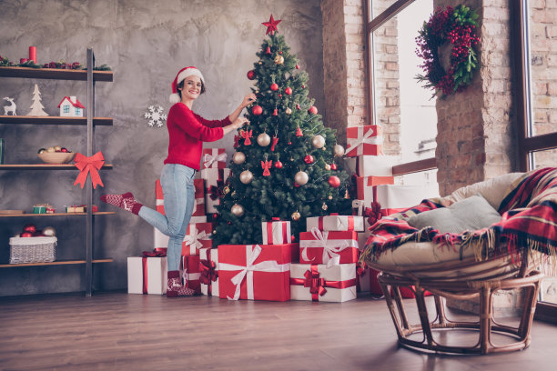可爱的小女孩的照片挂球，圣诞树，戴圣诞老人的头饰，红毛衣装饰客厅室内图片下载