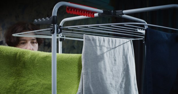 一个成熟的女人正在从晾衣架上取干衣服图片下载