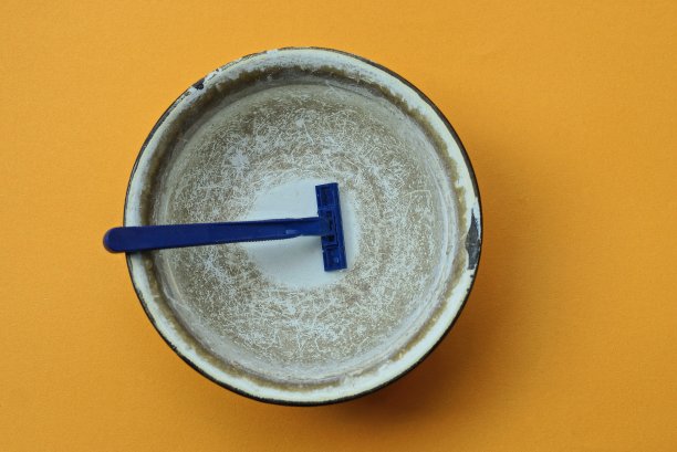 一把蓝色塑料剃须刀放在灰色金属碗里，放在水里图片下载