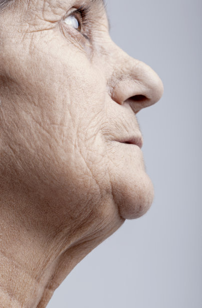 一个老妇人在灰色背景上向上看的侧视图图片图片下载