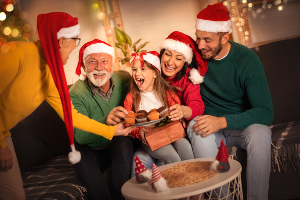 家庭圣诞与圣诞老人帽享受蛋糕，家庭庆祝图片下载