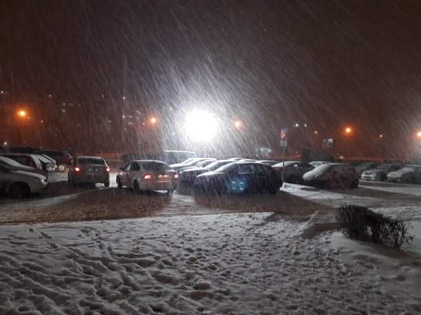 大雪映衬着灯光的灯笼。汽车在大雪中停在停车场图片下载