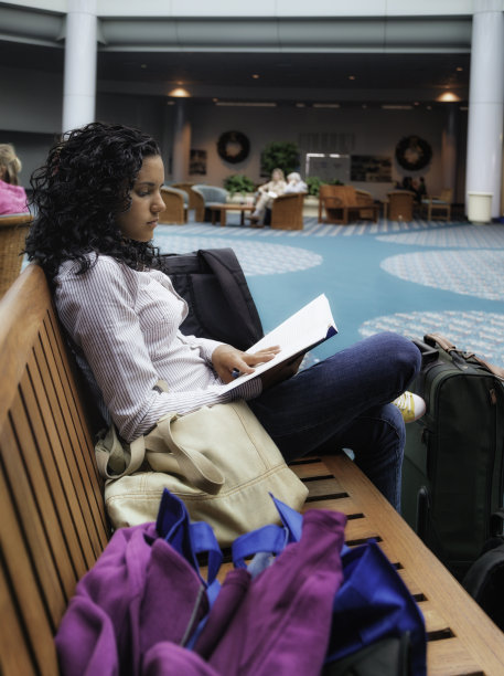 十几岁的旅行者在候机室等候时阅读预订图片下载