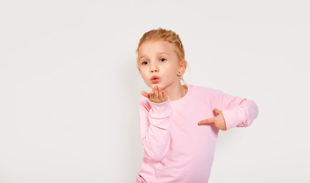 可爱的4-5岁小女孩送一个吻。孤立的白色背景。情感特写，嘴唇鞠躬。亲吻着粉红衣服脸上的表情。图片下载