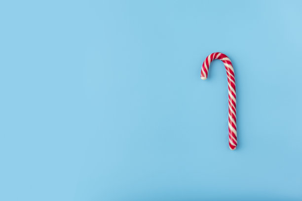 蓝色背景上的圣诞糖果。糖果形状，糖果拐杖。平躺，俯视图。本空间图片下载
