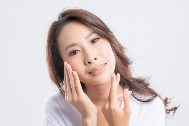 一个穿着浴巾的女人正在摸她的脸。图片下载