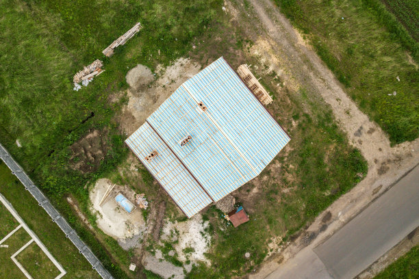 上下鸟瞰图，一个砖房与木质屋顶框架正在建设中。图片下载