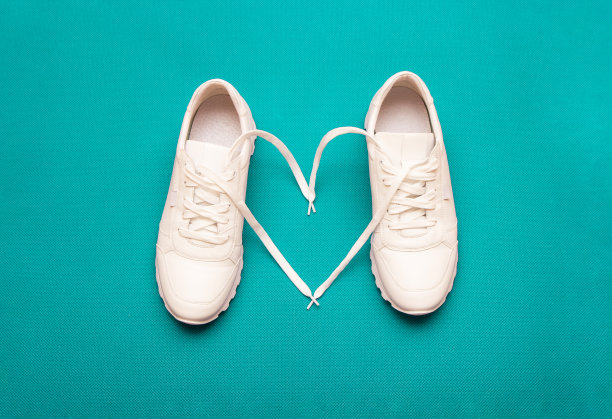 对健身的爱的概念。白色的心形运动鞋，在明亮的蓝色背景。有选择性的重点图片下载