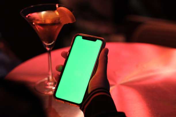 人们拿着绿色屏幕的智能手机在晚上的酒吧图片下载
