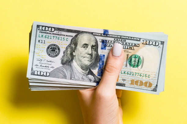 俯视图的女性手给一百美元钞票上的彩色背景。慈善捐赠理念图片下载