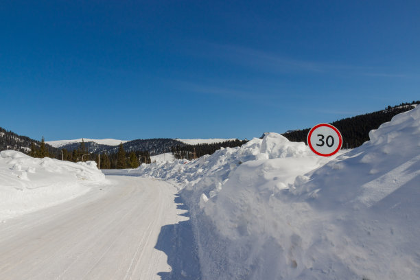在一个阳光明媚的日子里，驾驶在冰雪覆盖的道路上穿过额尔加基山脉，西萨彦山，西伯利亚，俄罗斯。冬天在弯弯曲曲的雪地上开车。图片下载
