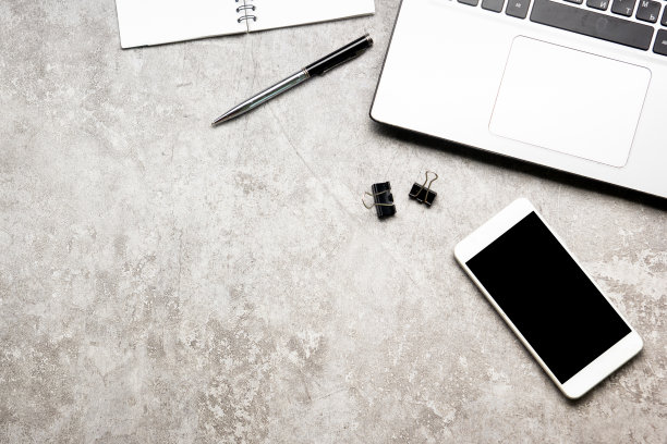 白色办公桌办公室，笔记本电脑，智能手机和其他工作用品与一杯咖啡。顶部视图与复制空间输入文本。设计师将工作空间的基本元素放在桌子上平铺。图片下载