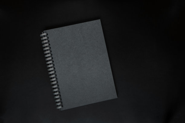 黑色背景上的黑色笔记本，模型照片。空白黑色封面模板与复制空间设计。黑色简约的设计理念。图片下载