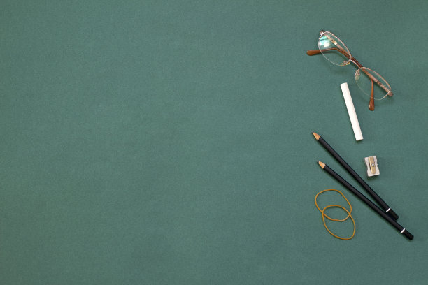 眼镜，铅笔和粉笔在绿色的背景上。教师节的概念图片下载