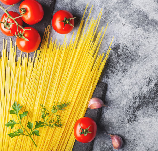 桌上放着意大利面，红番茄，大蒜和香草图片下载