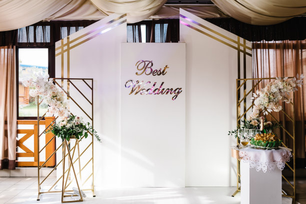 婚礼地点在白色和金色与文字最好的婚礼。优雅的婚礼拱门装饰玫瑰和白色的鲜花在婚礼区域。婚礼装饰。图片下载