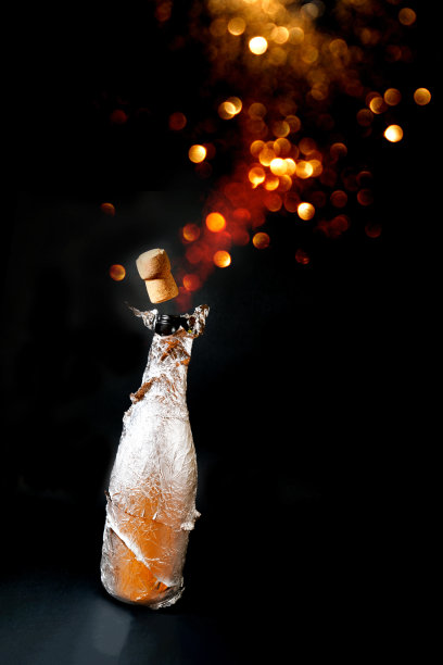 在黑色背景下开着一瓶香槟。图片下载