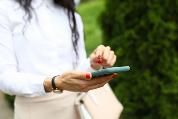 时尚的女人手里拿着一部智能手机，用手指指着屏幕图片下载