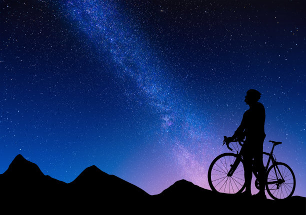 在银河的背景下，一辆公路自行车上的自行车的轮廓。美丽的夜景，一个公路自行车在山上星空的背景。图片下载