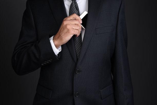 一名商人从西装外套内袋里拿出智能手机图片下载