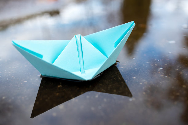 一艘蓝色的纸船漂浮在水面上。在户外。秋天的季节。带有副本空间的贺卡。领导的概念。自由的概念图片下载