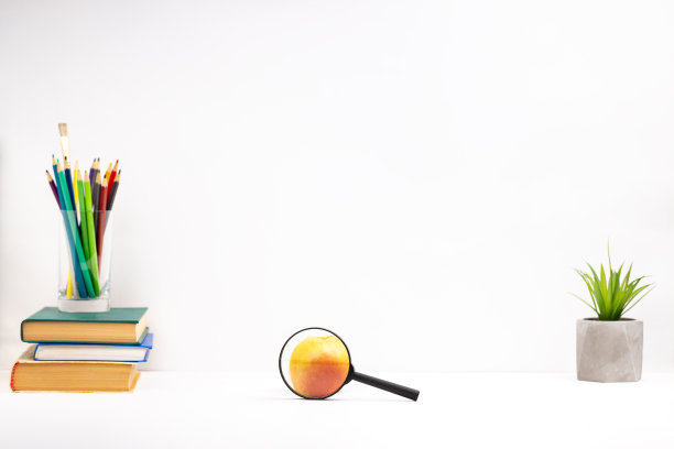 工作空间的侧视图，在灰色墙壁背景上有教育用品。放大镜，文具和书放在桌面上。教育学习理念图片下载