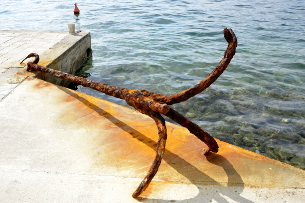 生锈的老锚，被遗忘在石头码头上图片下载