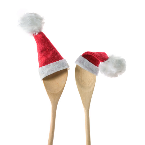 两个木制烹饪勺子与红色的圣诞老人帽孤立在白色的背景，圣诞晚餐邀请概念，复制空间图片下载