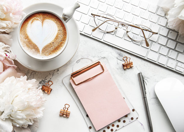 平躺顶视图女性办公室办公桌与鲜花。女性的工作空间有笔记本电脑，鲜花，牡丹，配件，笔记本，眼镜，咖啡在白色的背景。图片下载