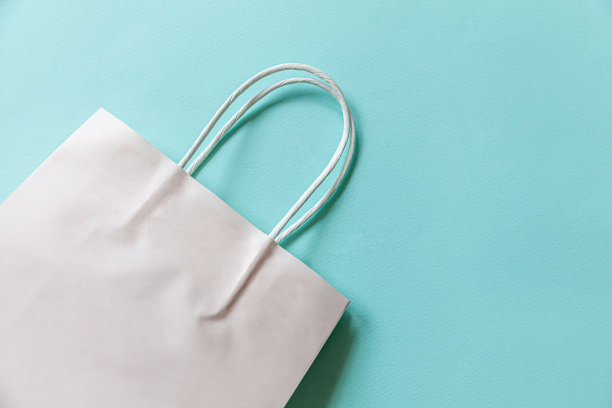 简单的简约设计购物袋孤立在蓝色柔和的背景。网上或购物中心购物狂概念。黑色星期五圣诞季大减价。平铺顶视图复制空间，模拟图片下载