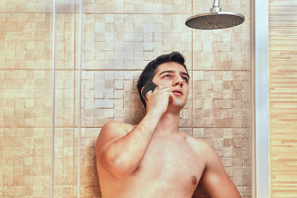 年轻貌美的白人男人在淋浴时打电话。图片下载