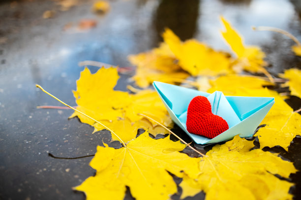 爱与浪漫的贺卡。蓝色纸船上的爱情符号。秋天的季节。友谊的概念。情人的概念图片下载