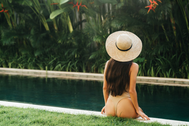 一个戴着太阳帽坐在游泳池里的女人图片下载