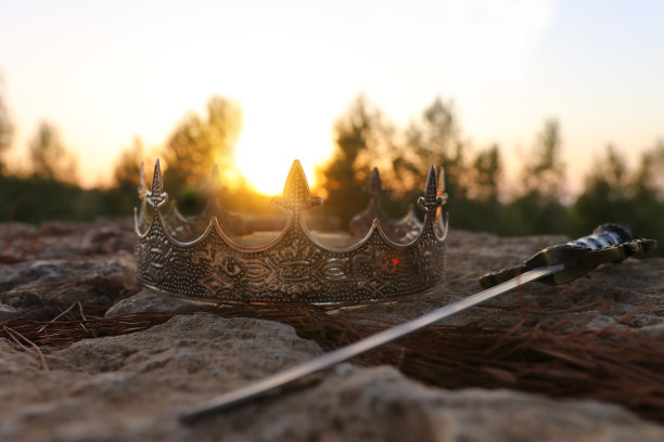 神秘而神奇的照片，银色的国王皇冠和剑在英国森林的石头。中世纪的概念。图片下载