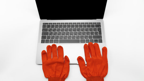 红色防护手套躺在笔记本旁边，近观。网络通信、网上购物或实验室工作的概念图片下载