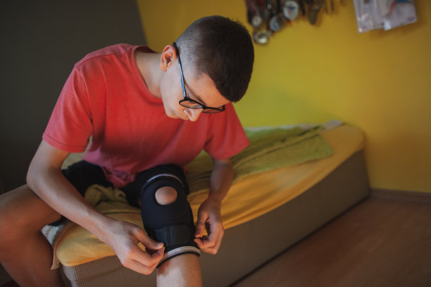 一名青少年在使用轮椅前在腿上放置矫形器械图片下载