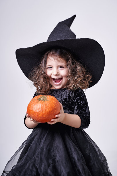 戴着帽子，手里拿着南瓜的滑稽女巫女孩图片下载