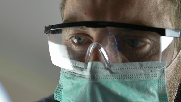 戴外科口罩的医生使用非接触式体温计检测冠状病毒感染者图片下载