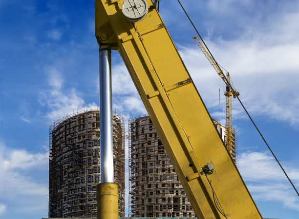 俄罗斯莫斯科，建筑机器(挖掘机或起重机)的一部分，背景是多层建筑和脚手架(新的住宅综合体)图片下载