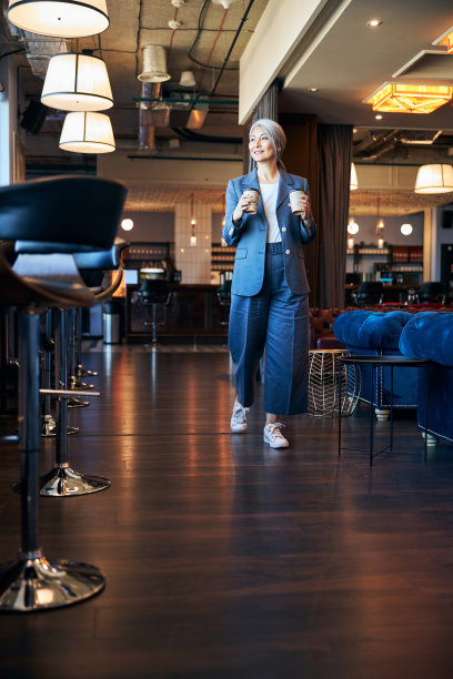 美丽快乐的女人拿着咖啡走在咖啡馆里图片下载