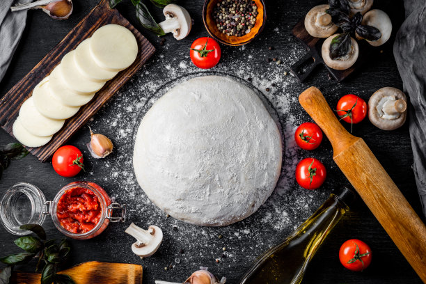 制作披萨面团的原料，马苏里拉奶酪，西红柿，蘑菇，橄榄油和罗勒在黑色背景上，俯视图图片下载