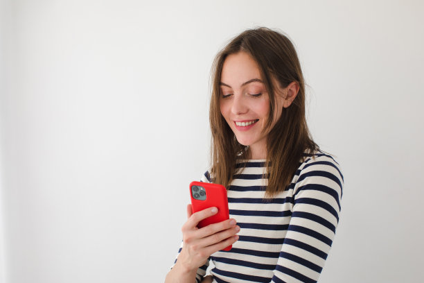 微笑的女人在家里用智能手机冲浪图片下载