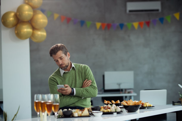 一个人在办公室聚会时发手机短信，很不高兴。图片下载