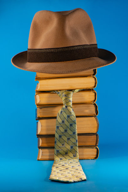 帽子躺在一堆书和一条领带，蓝色的背景图片下载