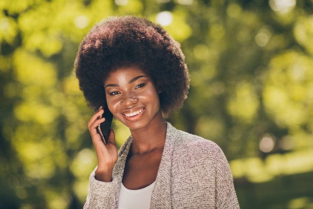 照片积极的非洲裔美国女孩打电话在夏天的周末在树城市木材户外公园打电话图片下载
