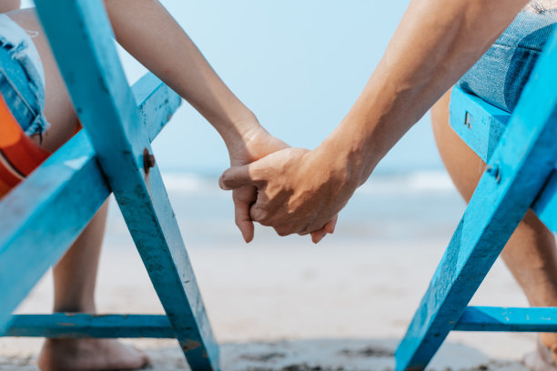 一对夫妇坐在海滩的躺椅上。蜜月，爱情，旅行或度假的概念。图片下载