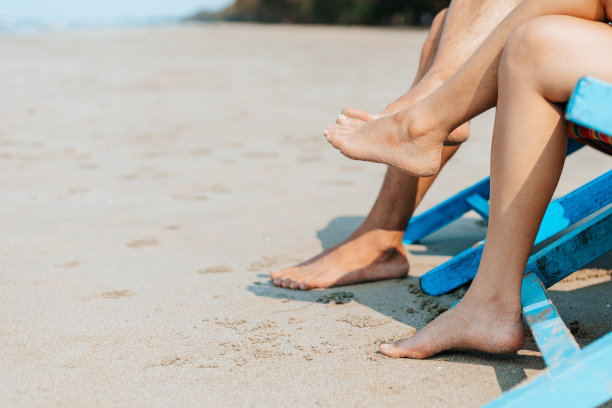 一对夫妇坐在海滩的躺椅上。蜜月，爱情，旅行或度假的概念。图片下载