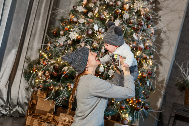 妈妈和女儿在圣诞树旁玩耍。为圣诞节拍摄照片。大美丽的圣诞树在灰色风格图片下载