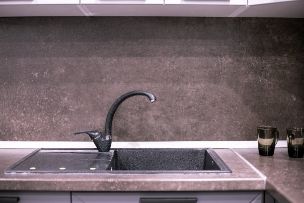 黑色人造石水槽，厨房大水龙头，棕色台面和后挡板图片下载