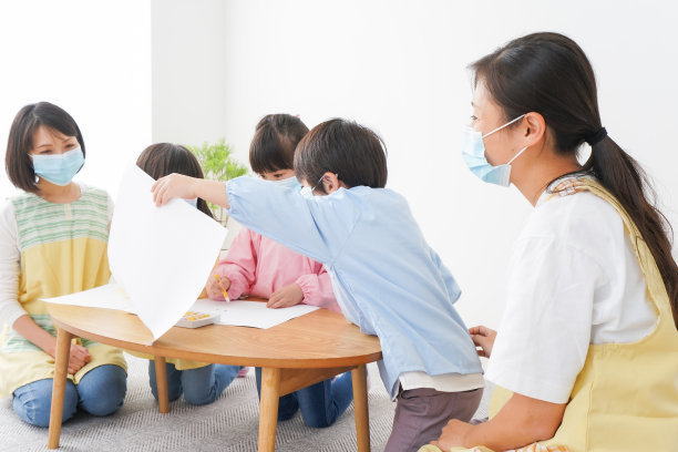 一个幼儿园小朋友和他的老师戴着面具在画画图片下载